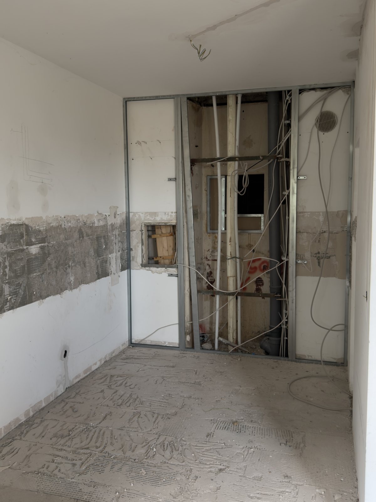 Küche während der Sanierung mit offener Vorwandinstallation und abgeschlagenem Fliesenspiegel